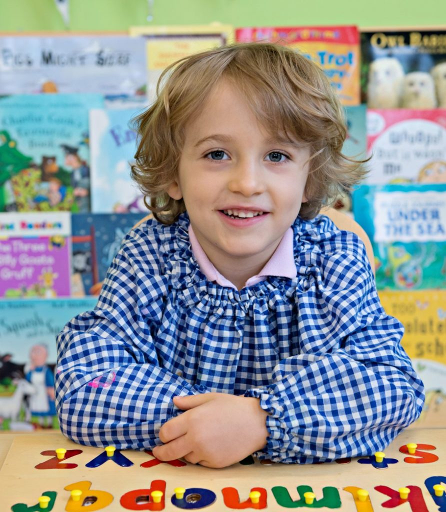 nursery aged school photo of boy at desk